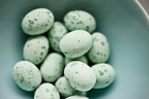 a blue bowl filled with green speckled eggs