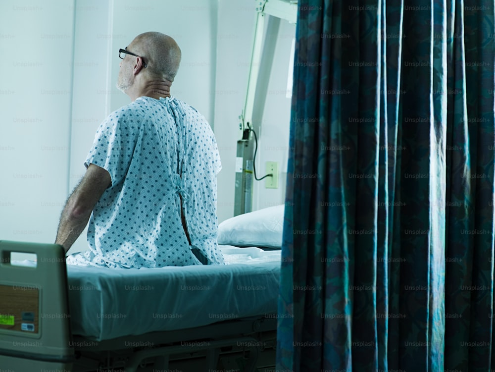 um homem em um vestido de hospital sentado em uma cama de hospital