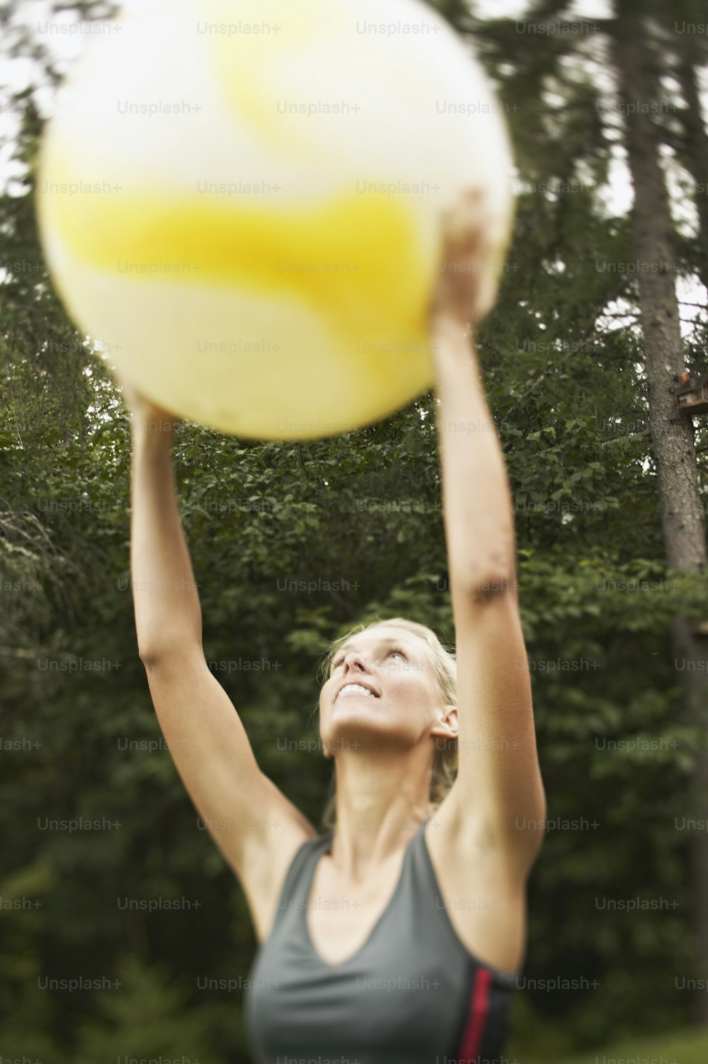a woman reaching up to catch a yellow frisbee