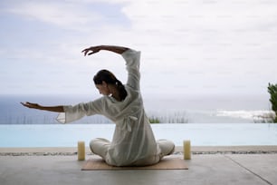a woman in a white outfit doing a yoga pose