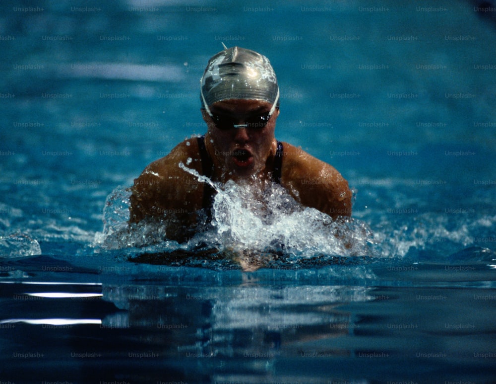 Ein Mann, der mit einem Helm in einem Pool schwimmt