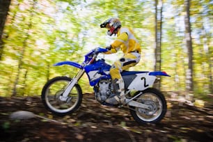 a man riding a dirt bike through a forest