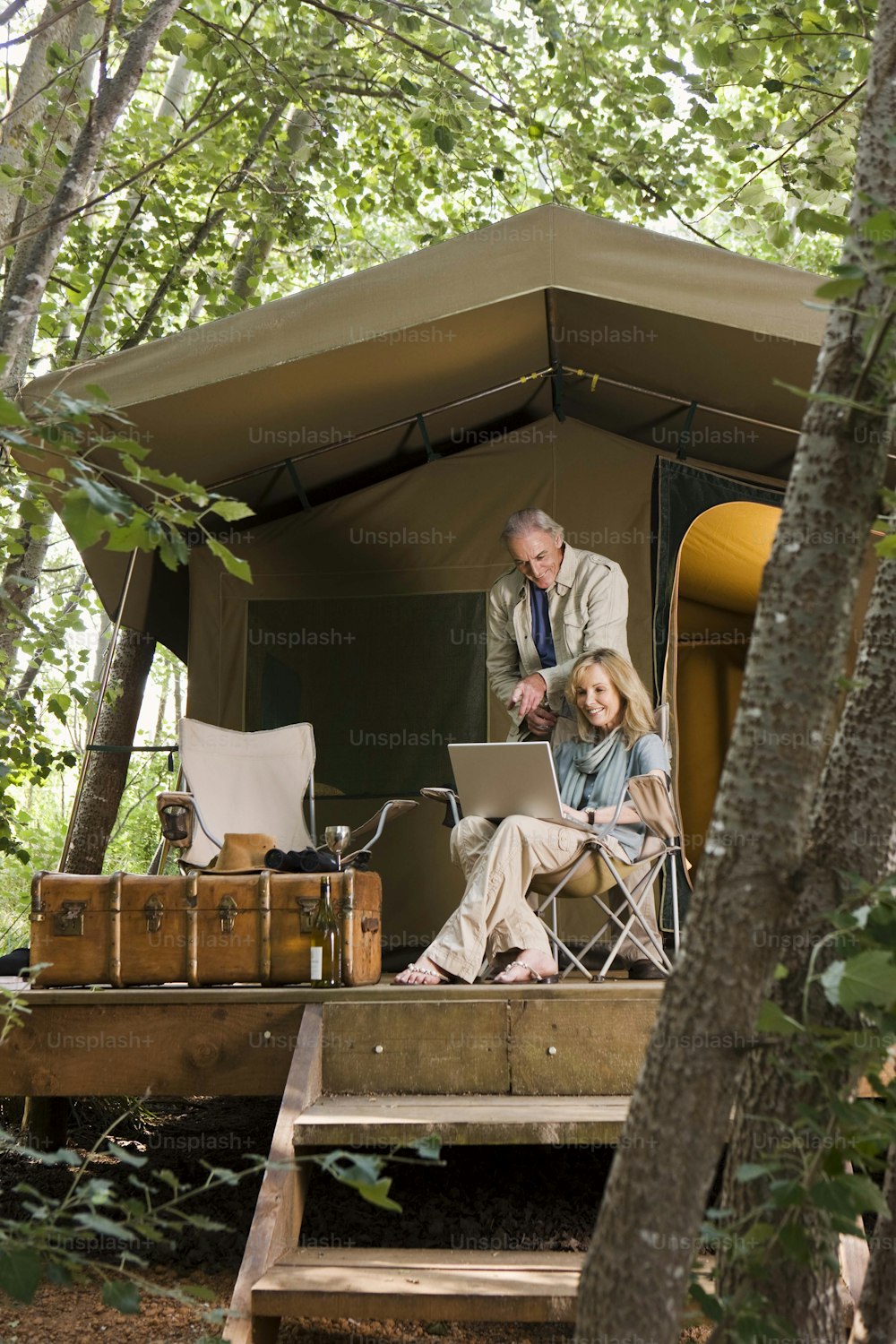a man and a woman sitting in a tent in the woods