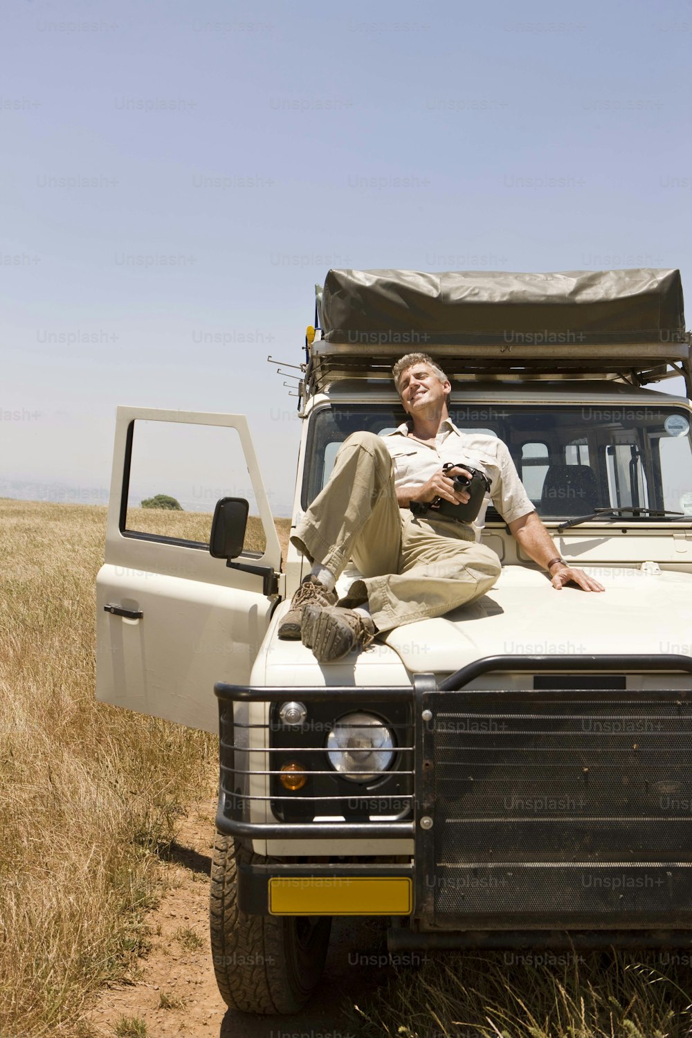 a man sitting on top of a truck in a field