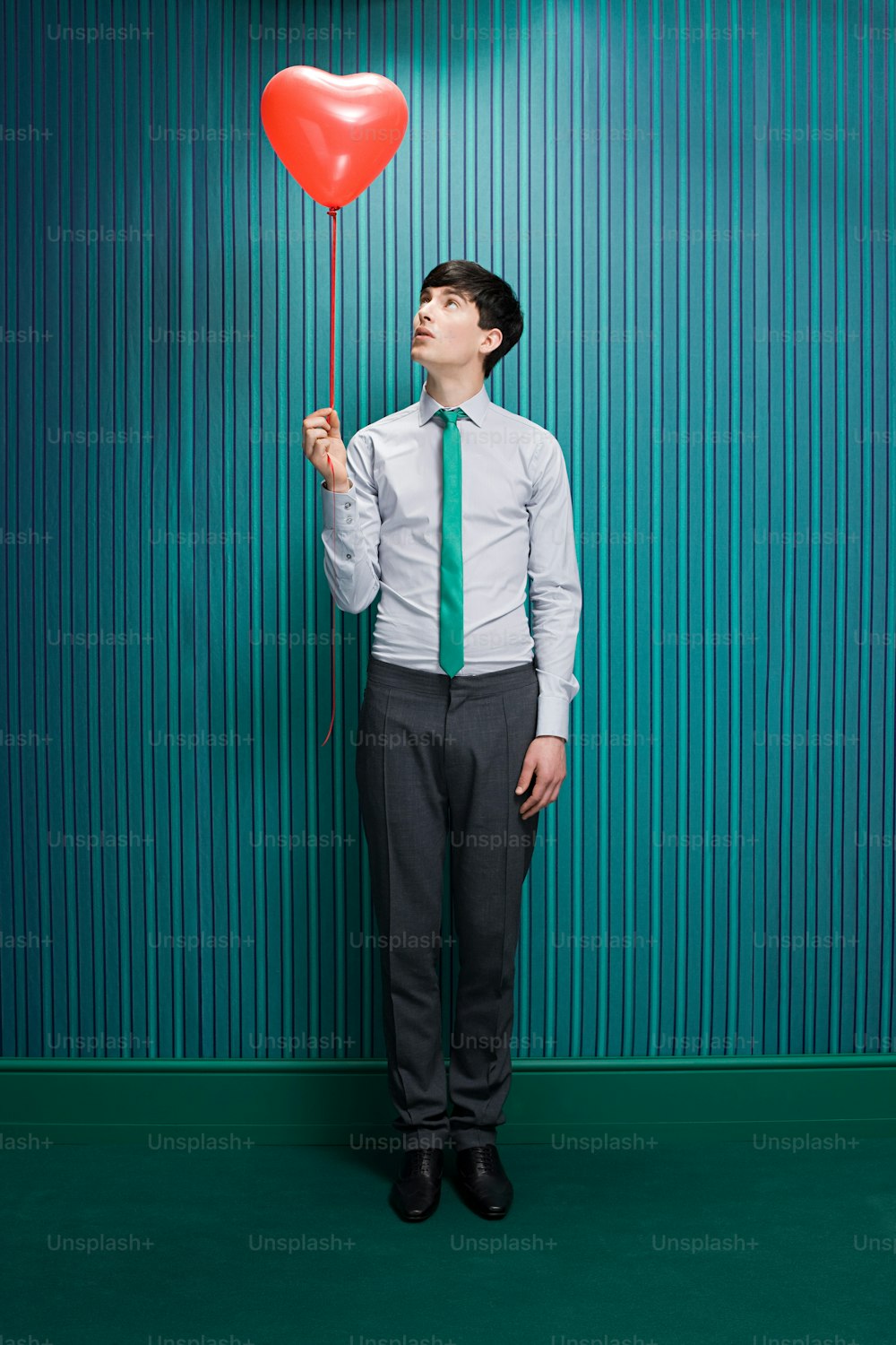 a man in a tie holding a heart balloon