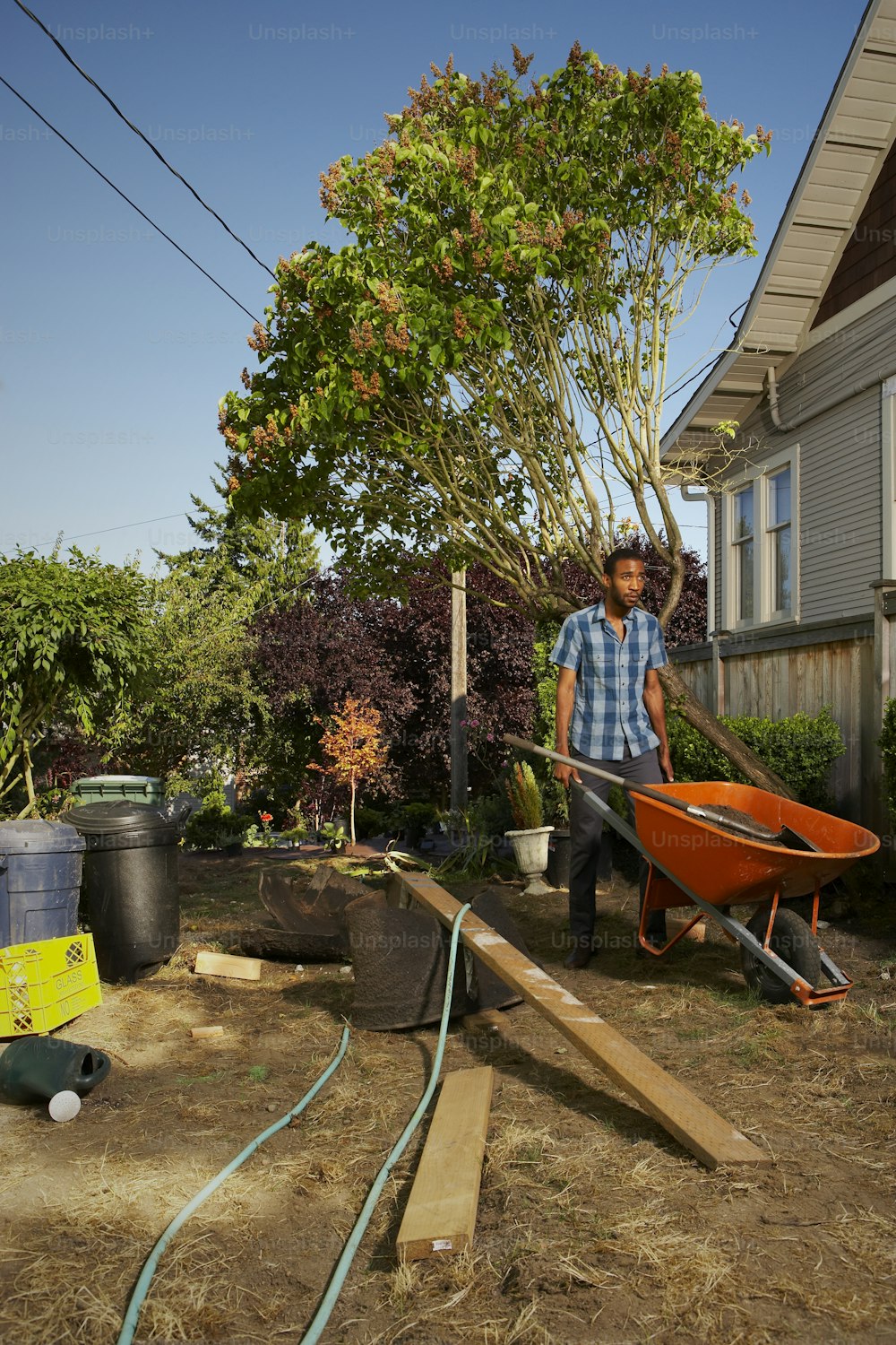 a man holding a wheelbarrow in a yard