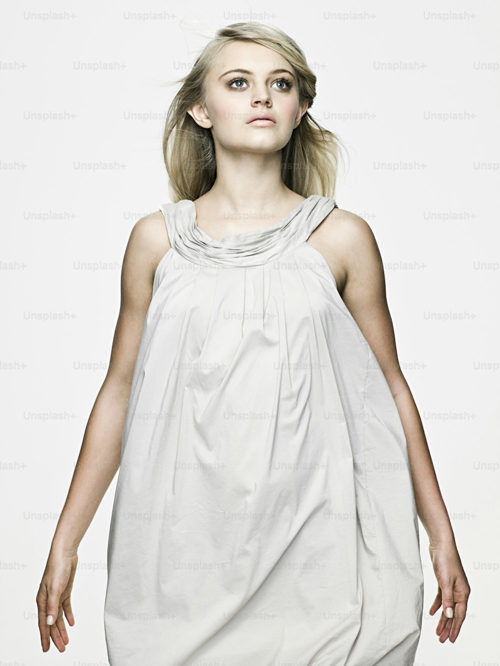 Una mujer con un vestido blanco con las manos en los bolsillos