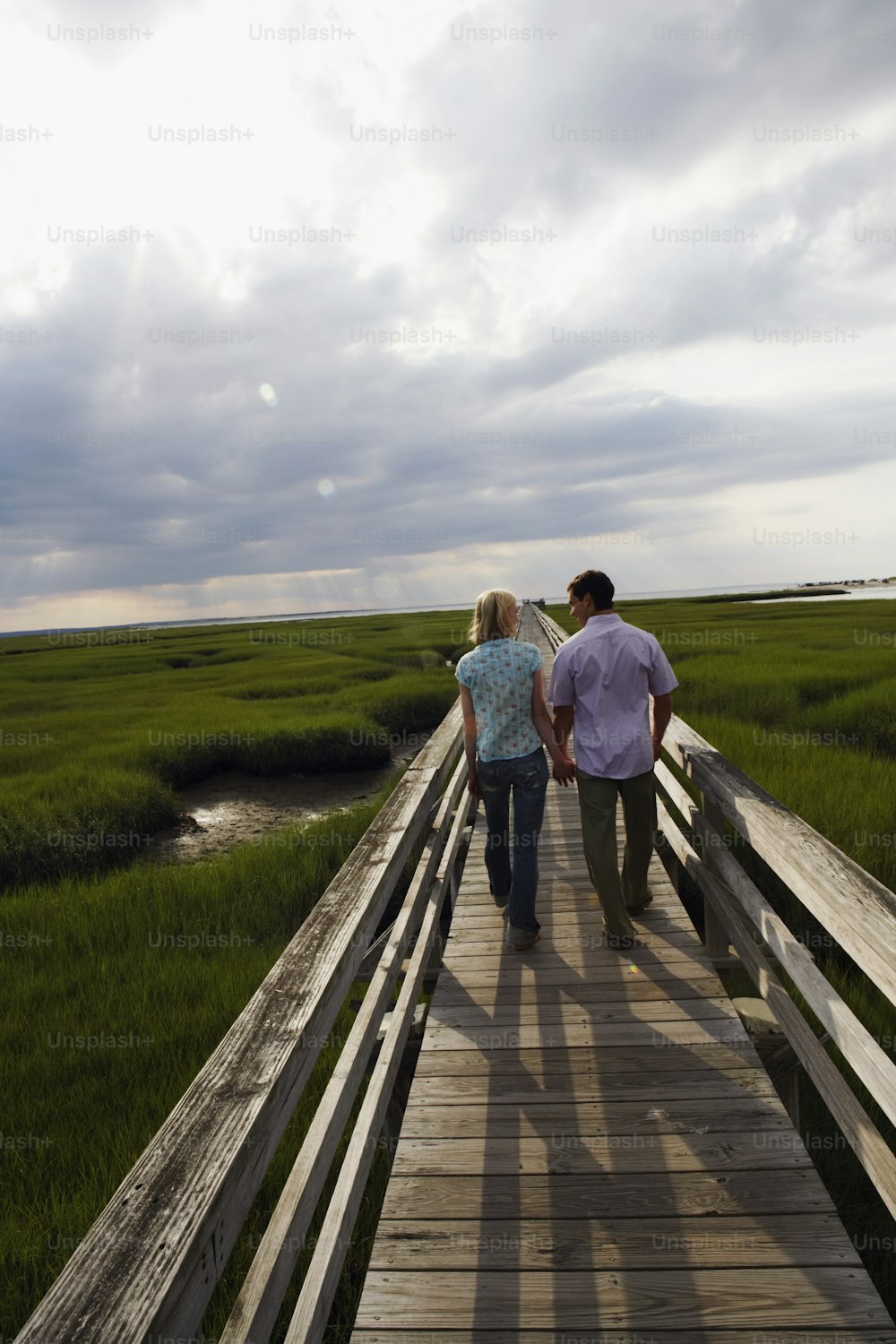 a man and a woman walking on a wooden bridge