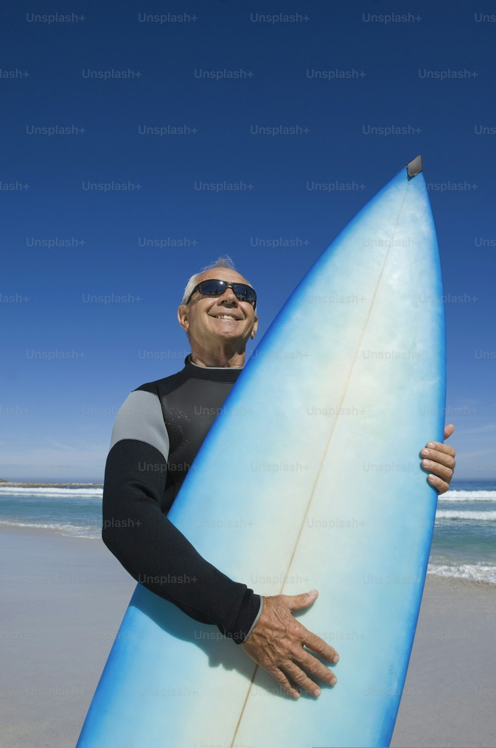 um homem segurando uma prancha de surf azul em uma praia