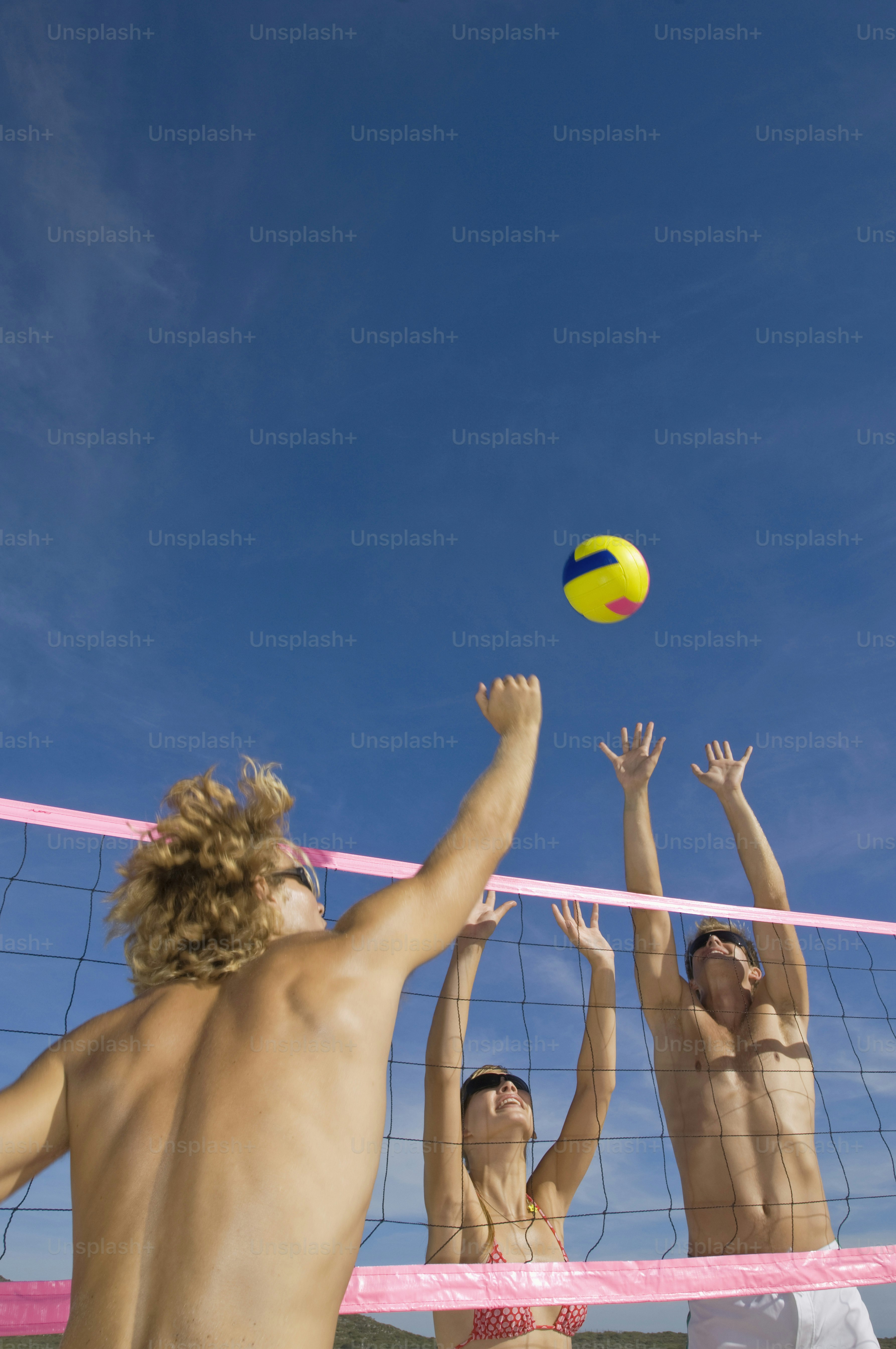 a group of people playing volleyball on a beach