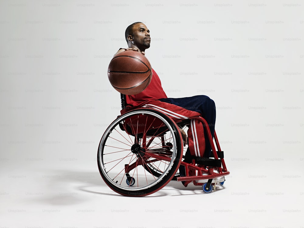 um homem em uma cadeira de rodas segurando uma bola de basquete