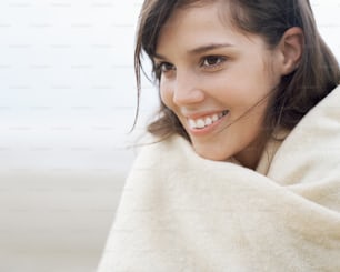 uma mulher enrolada em um cobertor sorrindo para a câmera
