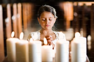 uma jovem menina acendendo velas em uma igreja