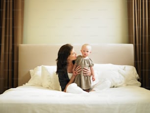 a woman holding a baby on top of a bed