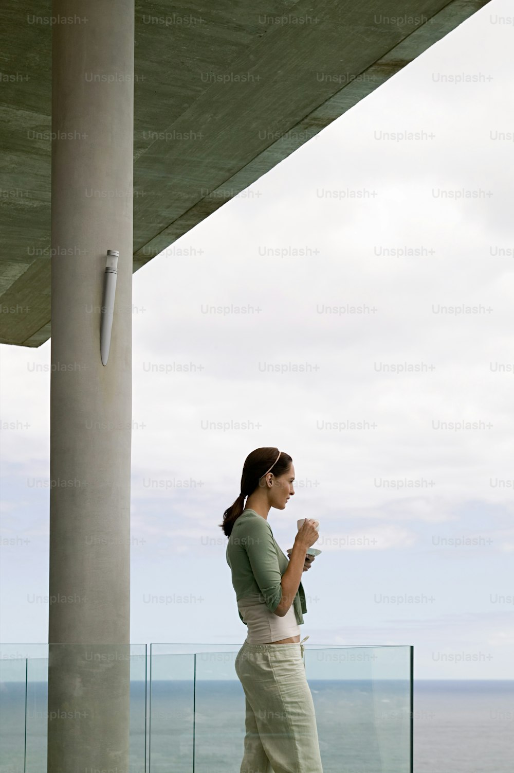 uma mulher em pé em uma varanda ao lado do oceano