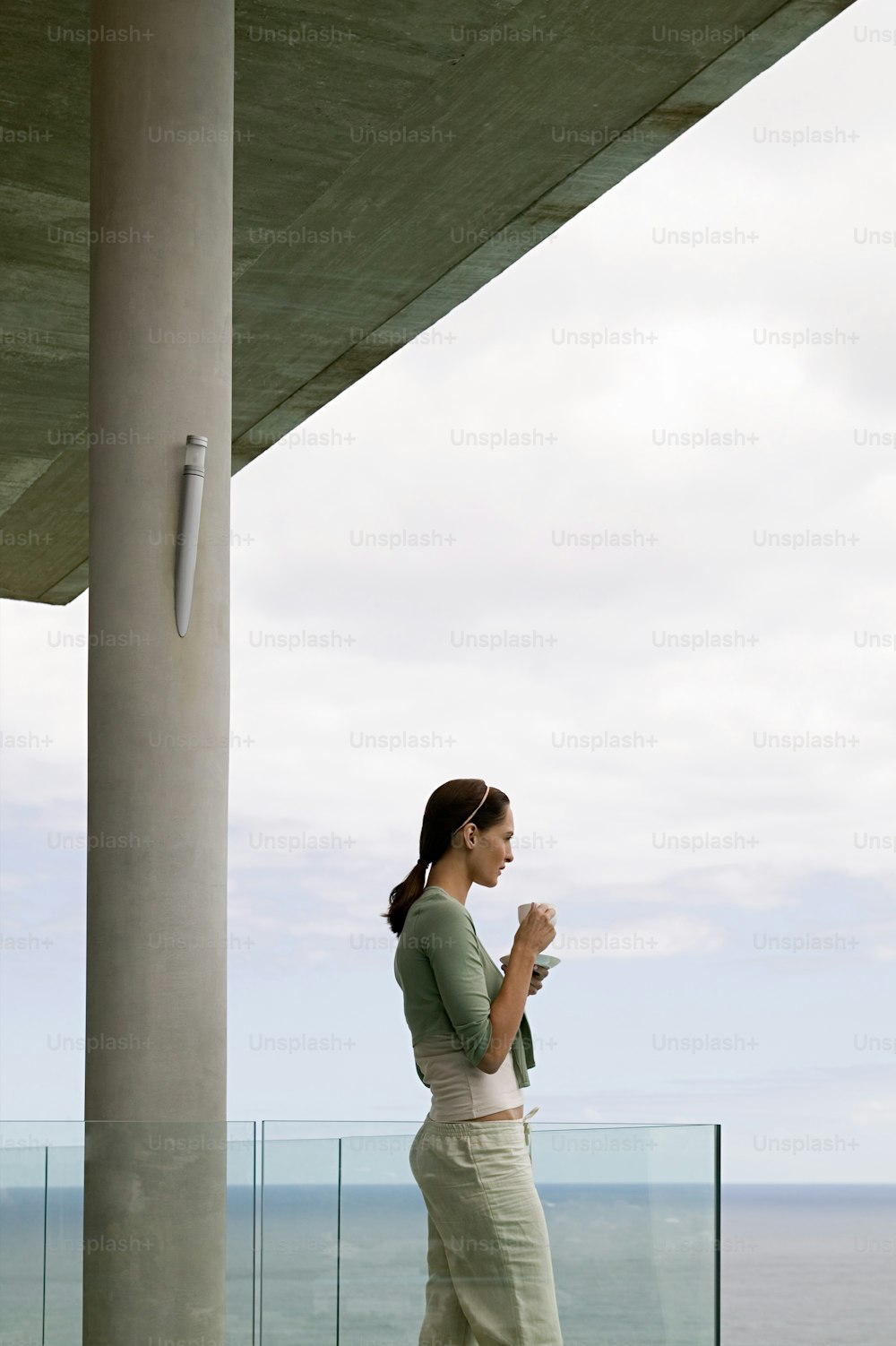 a woman standing on a balcony next to the ocean