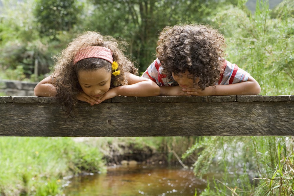 Deux jeunes filles penchées sur un pont en bois