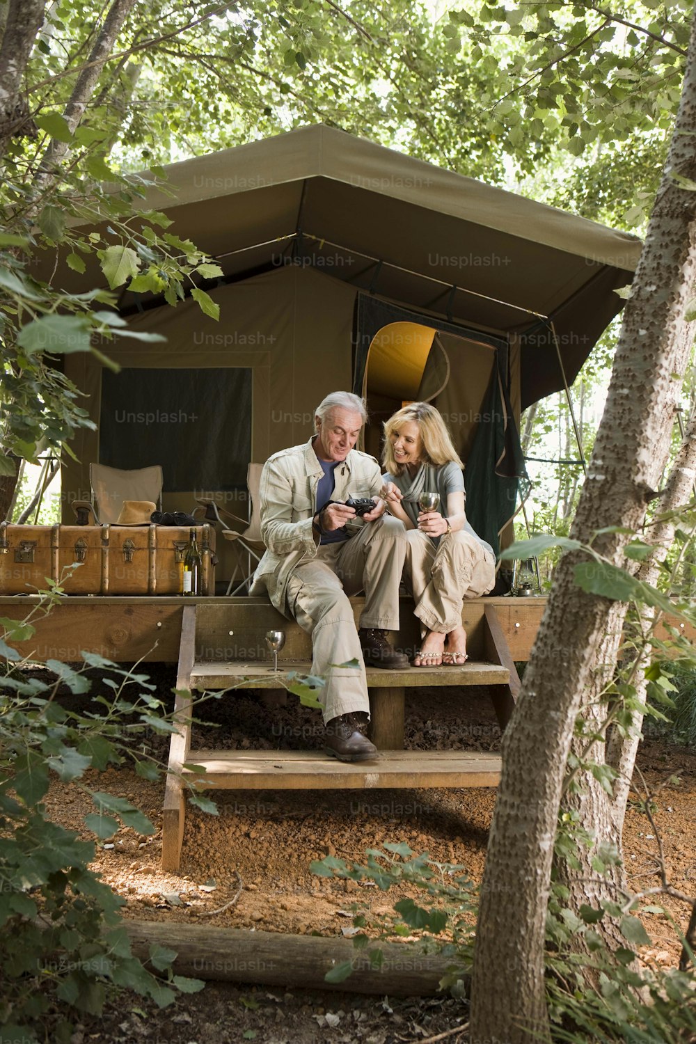 a man and a woman sitting on a bench in front of a tent