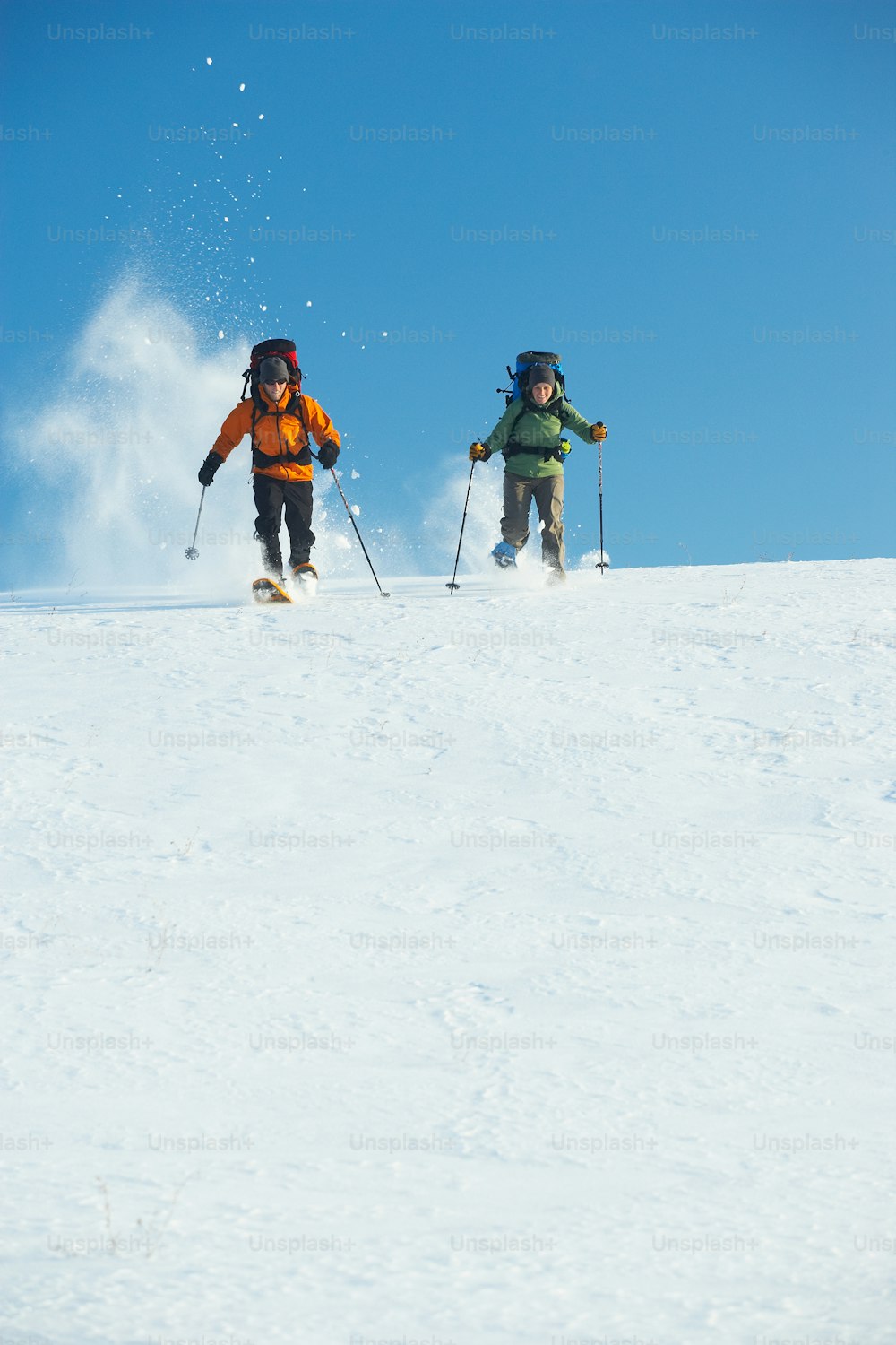 a couple of people riding skis down a snow covered slope