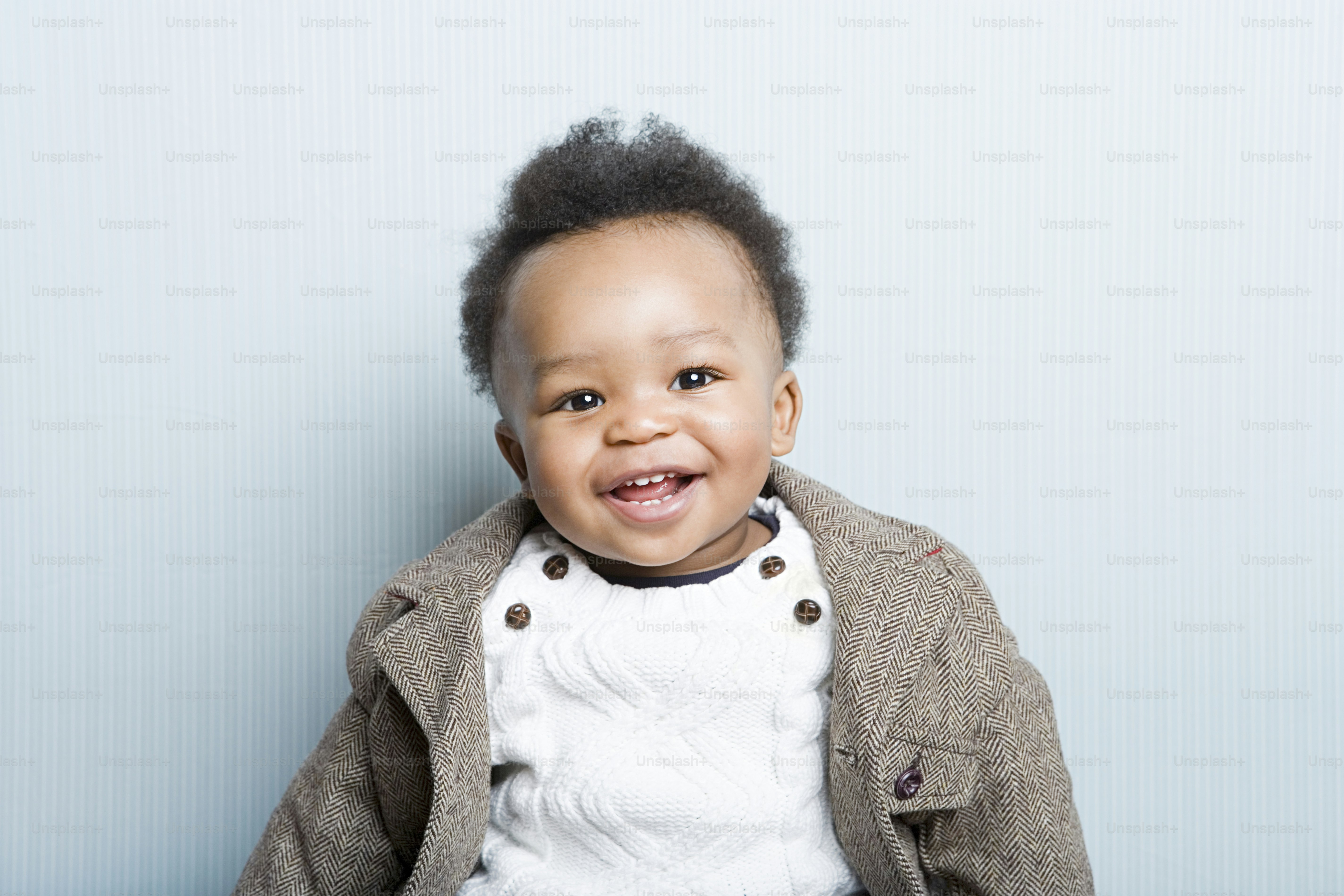 a little boy sitting on the ground with a smile on his face