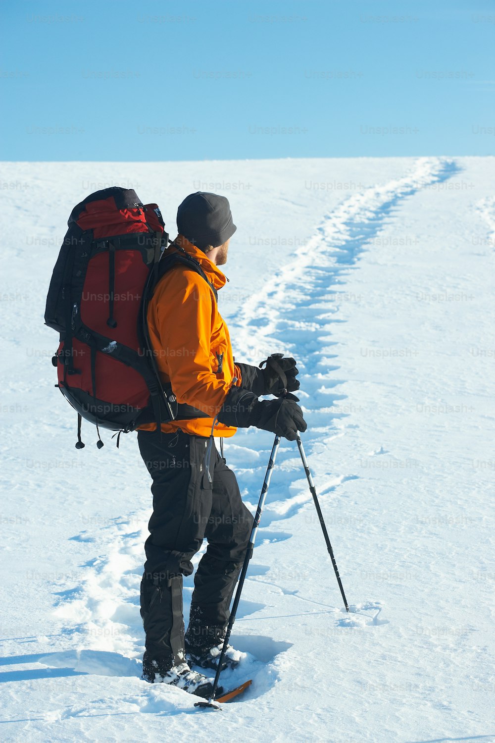 Un homme avec un sac à dos et des skis marchant dans la neige