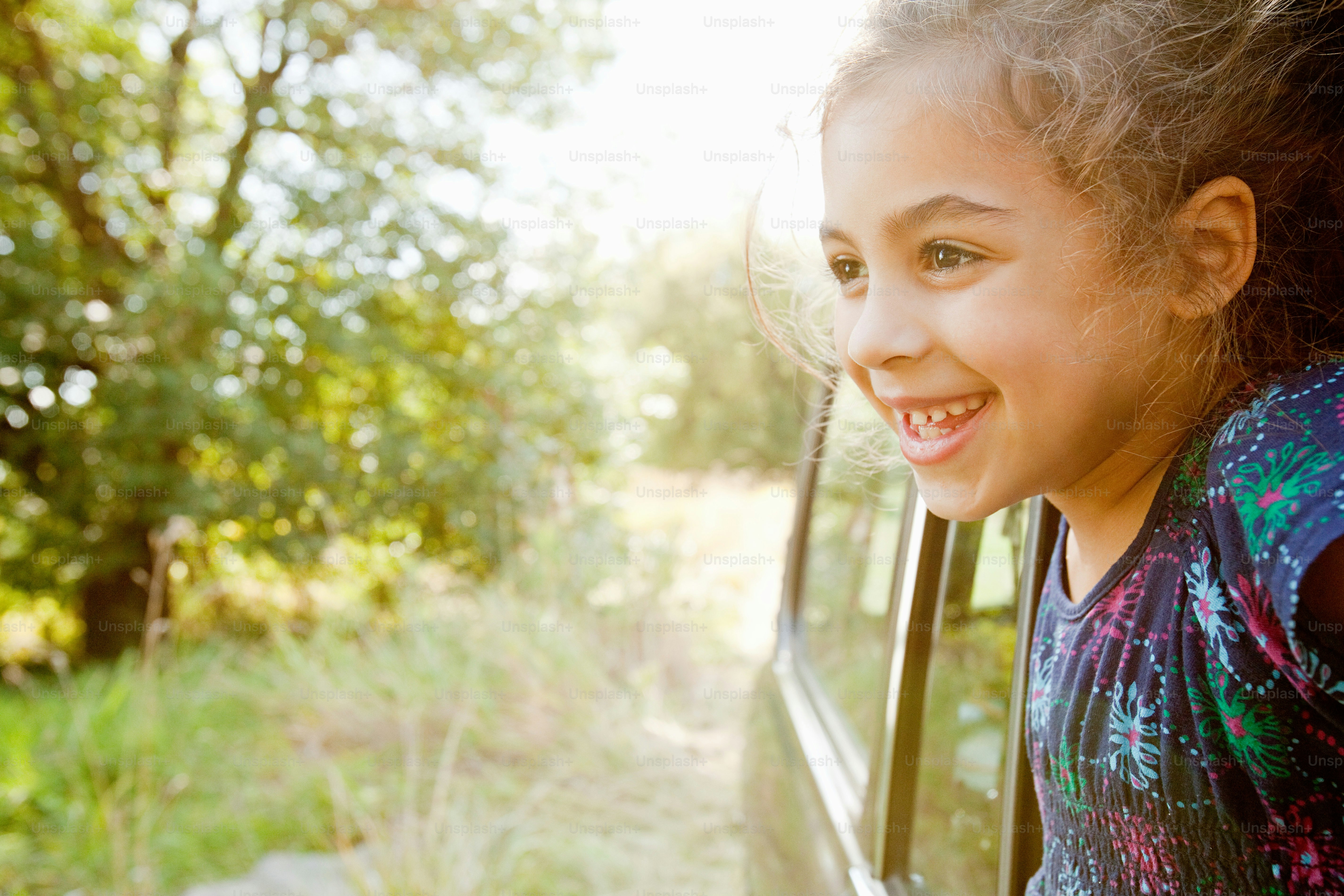 a young girl smiles out of a car window