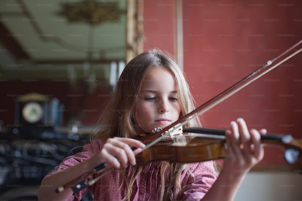 a young girl playing a violin in a room