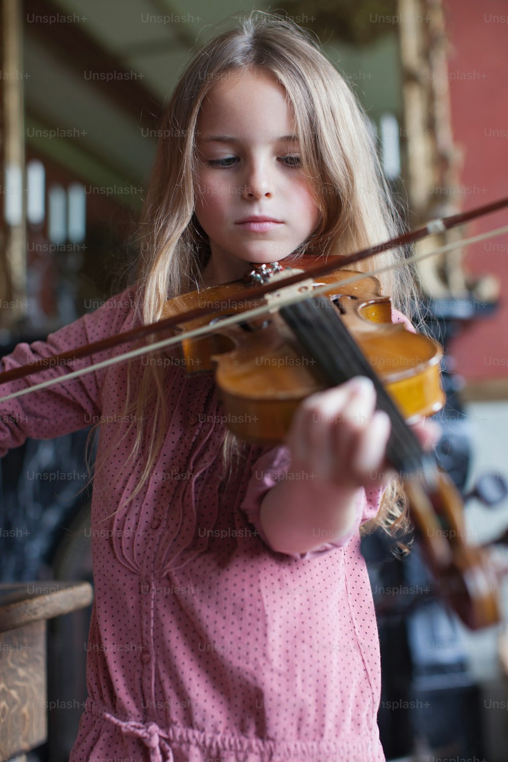 a little girl playing a violin in a room