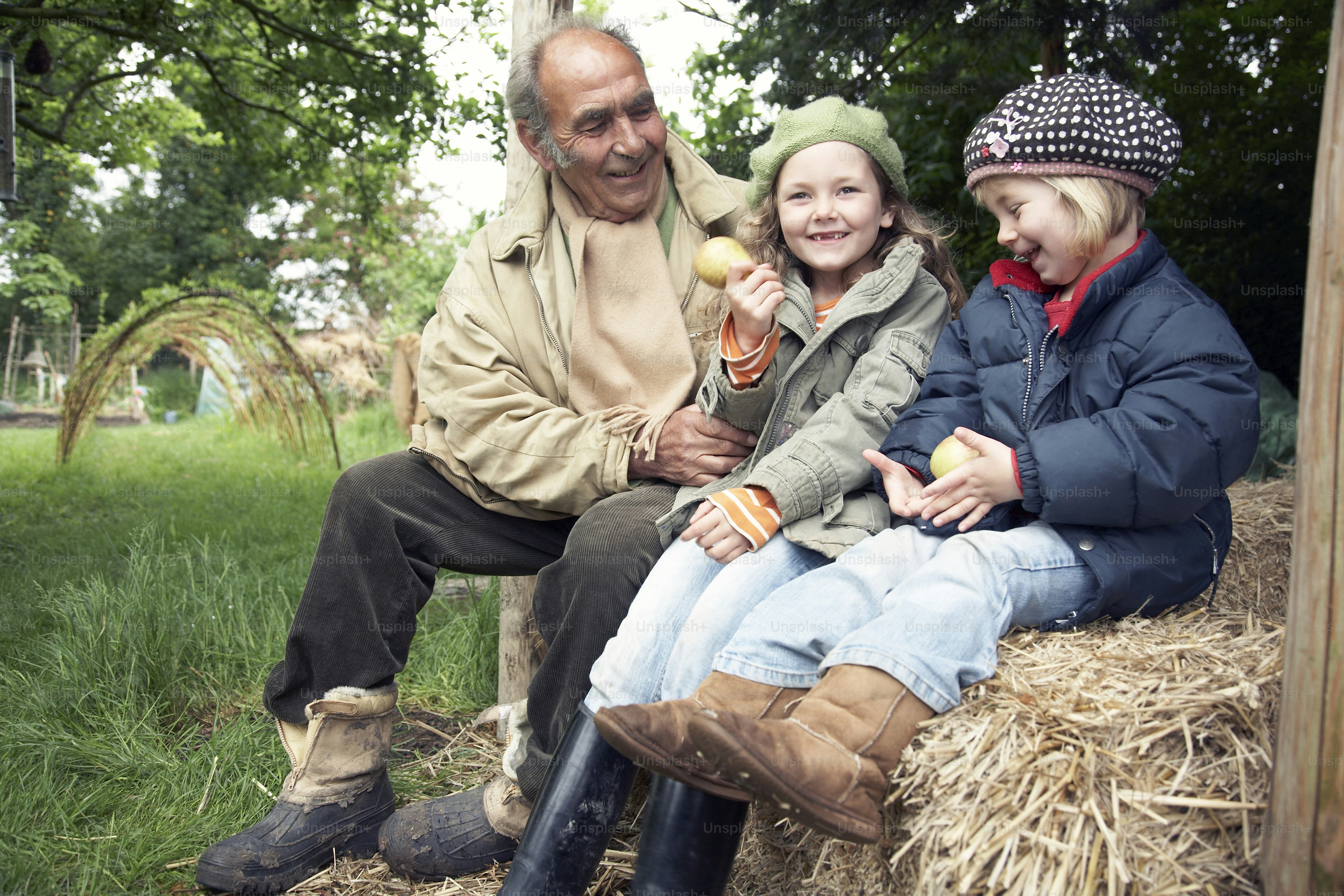 Un uomo e due bambini seduti su una balla di fieno