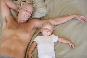 Un homme allongé sur un lit à côté d’un petit enfant