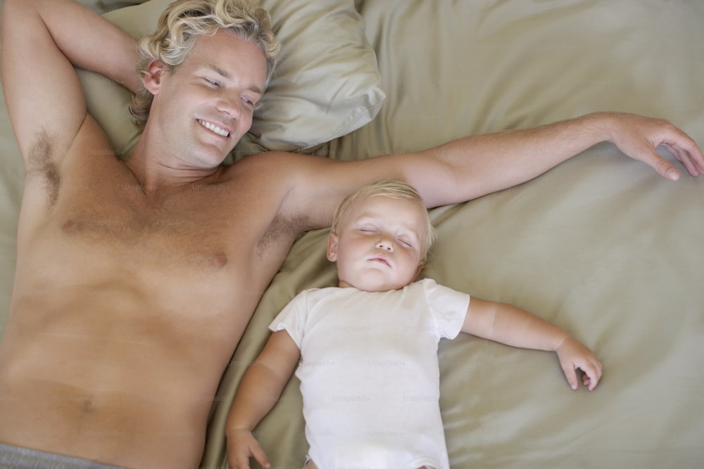 a man laying on a bed next to a small child