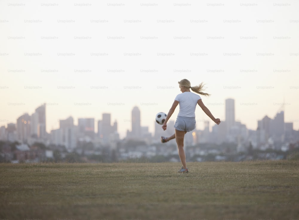 a girl kicking a soccer ball in a field