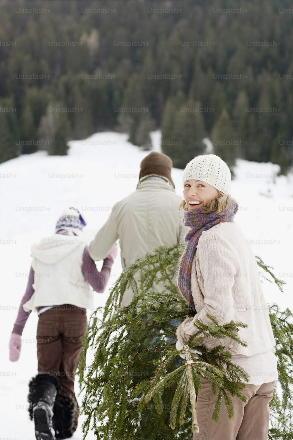 two people carrying a christmas tree in the snow