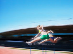 Eine Frau im grünen Bikini springt über eine Hürde