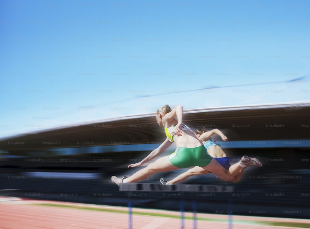Una mujer en bikini verde saltando sobre un obstáculo