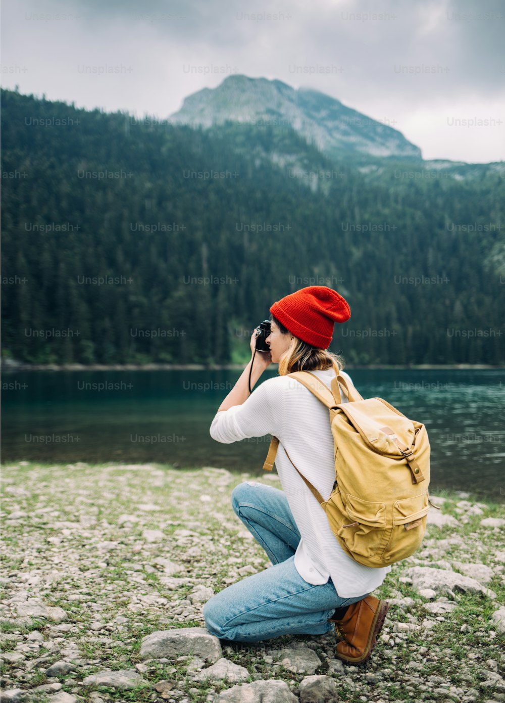 Hipster girl with camera enjoy mountain adventure. Woman crouching and taking photographs.
