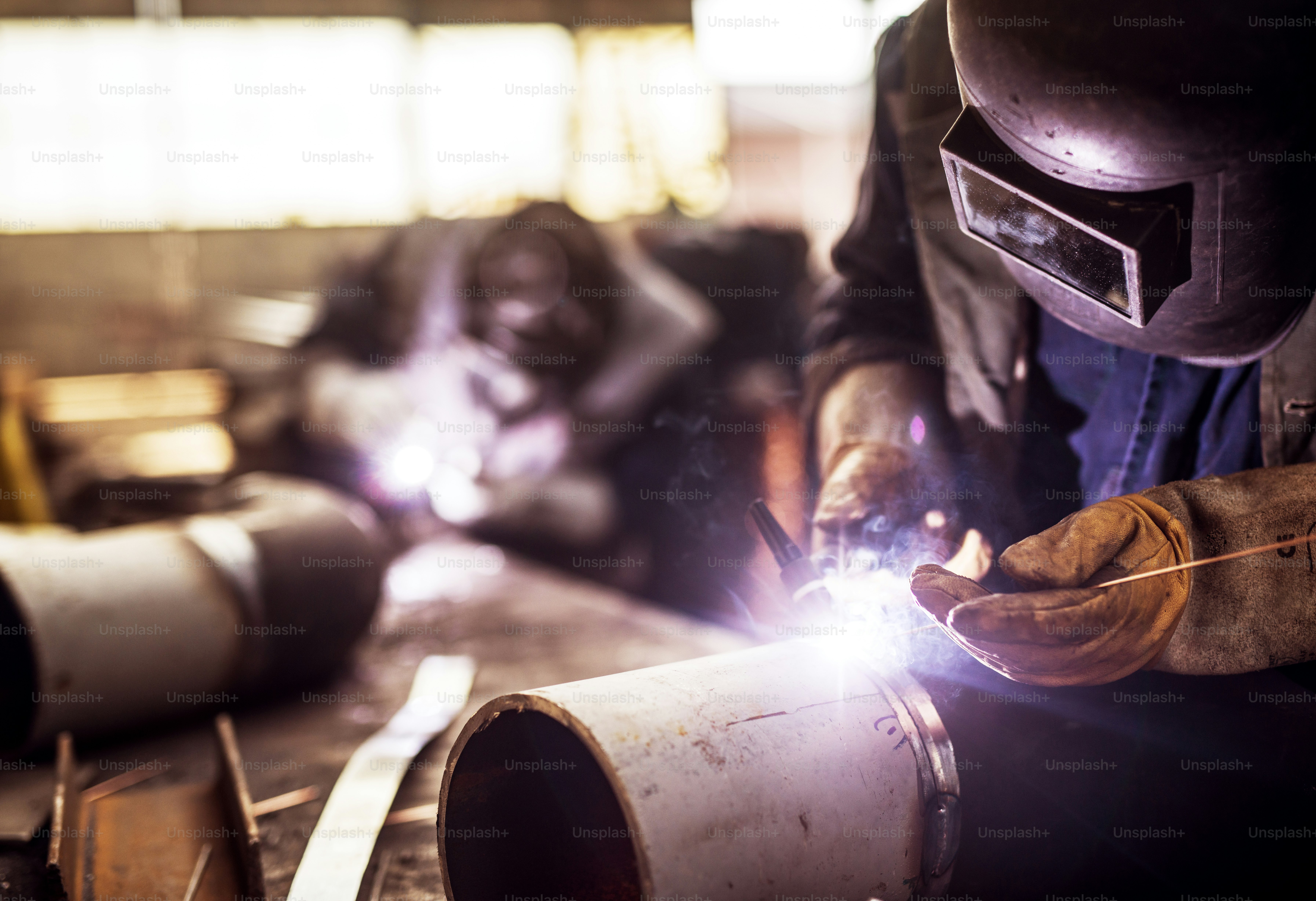 Close up of a male fabric worker cutting metal pipe with an electric grinder in workshop.