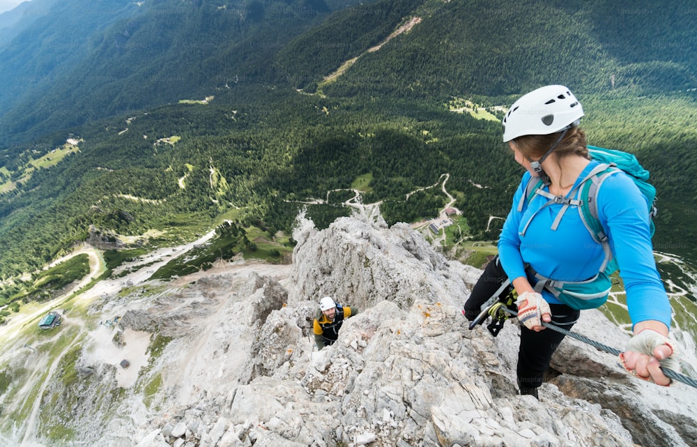 two young attractive mountain climbers on very exposed Via Ferrata in Alta Badia in the Italian Dolomites