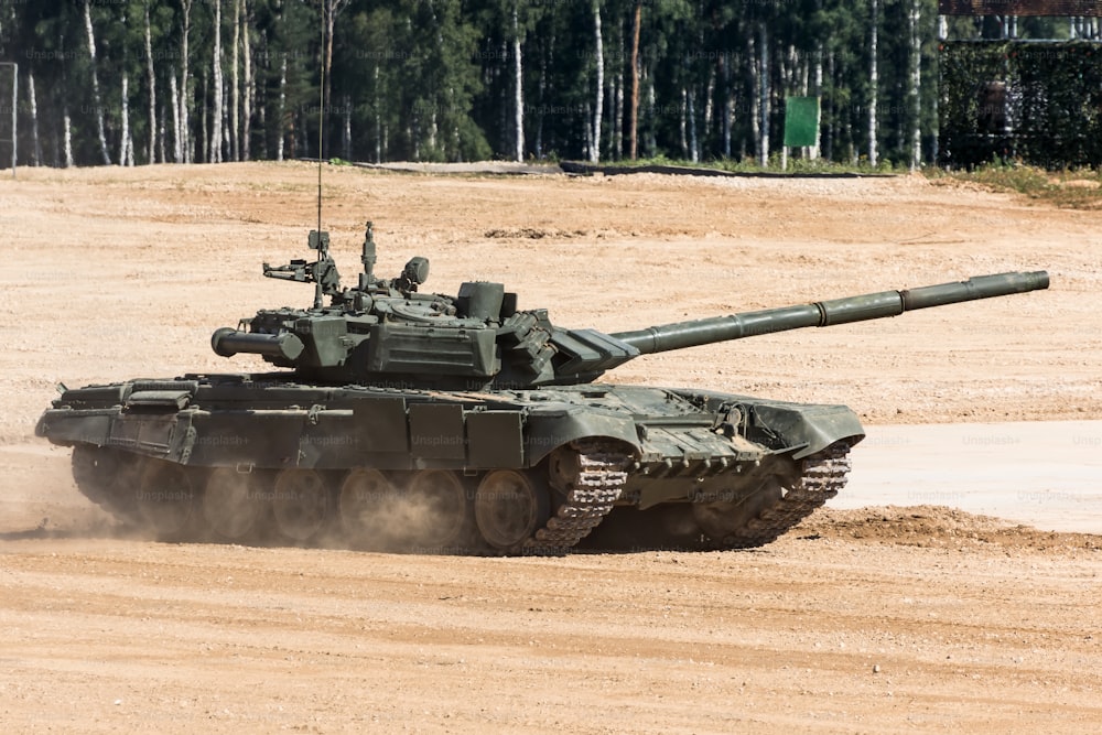 Military or army tank ready to attack and moving over a deserted battle field terrain