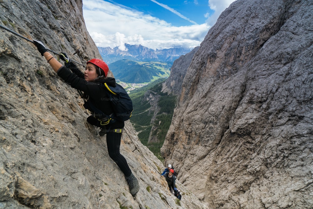 três alpinistas em uma difícil Via Ferrata nas Dolomitas em Alta Badia, no sul do Tirol, na Itália