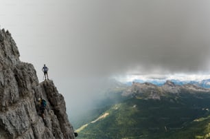 dos jóvenes y atractivos alpinistas en una vía ferrata muy expuesta en Alta Badia, en los Dolomitas italianos