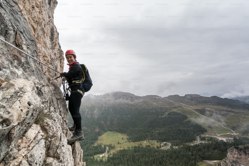 jovem alpinista feminina atraente em uma íngreme e exposta Via Ferrata em Alta Badia, no sul do Tirol, nas Dolomitas italianas