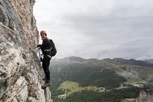 giovane attraente alpinista su una ripida ed esposta via ferrata in Alta Badia in Alto Adige nelle Dolomiti italiane