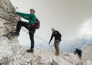 grupo de jóvenes alpinistas en una empinada vía ferrata con una grandiosa vista de los Dolomitas italianos en Alta Badia detrás de ellos