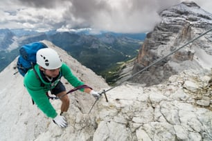 jovem alpinista masculino em uma íngreme e exposta Via Ferrata em Alta Badia, no sul do Tirol, nas Dolomitas italianas