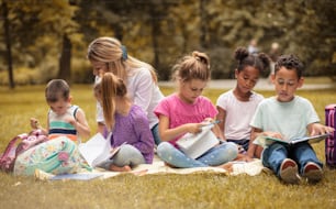 They love being creative. Large group of children and teacher have class at nature.