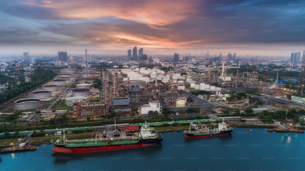 Oil refinery factory and tanker boat with beautiful sky at dusk for energy or gas industry or transportation background.