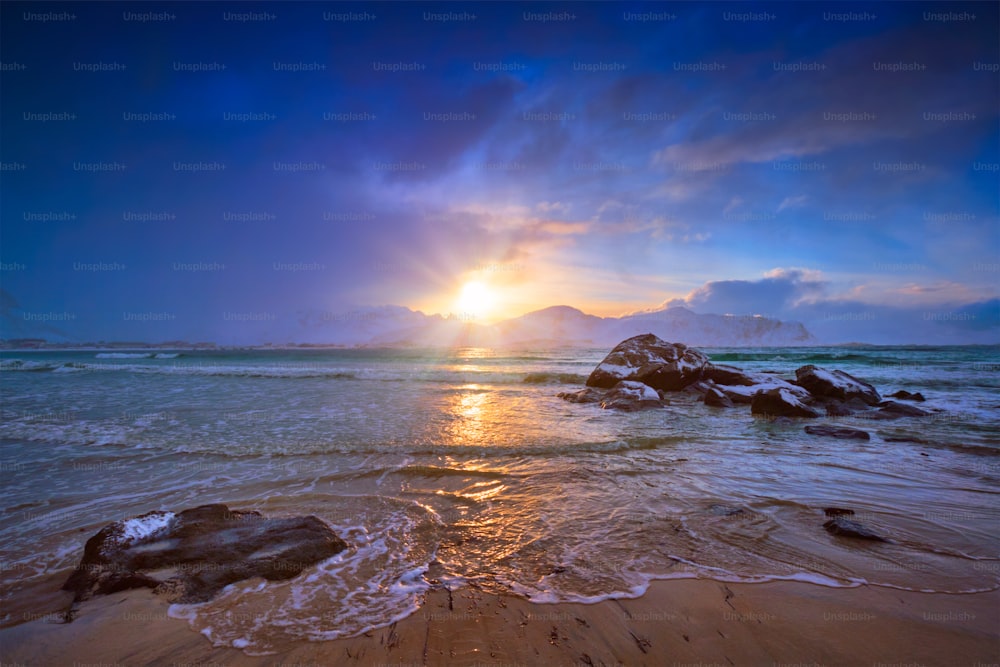 Beach of Norwegian sea on rocky coast in fjord on sunset. Skagsanden beach, Lofoten islands, Norway