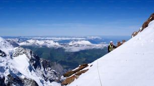 alpinista feminina em uma neve íngreme e gelo no lado da montanha com uma vista fantástica da paisagem montanhosa circundante e dos picos das montanhas em um belo dia de verão nos Alpes Suíços em Moench acima de Grindelwald