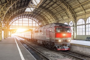 Passenger train with a diesel locomotive at the station under the roof